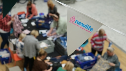 Close up of a bunting flag with the Newlife logo on it over a table at a charity event.