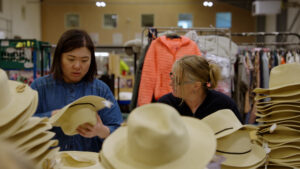 This picture shows two women pricing hats in the Newlife warehouse
