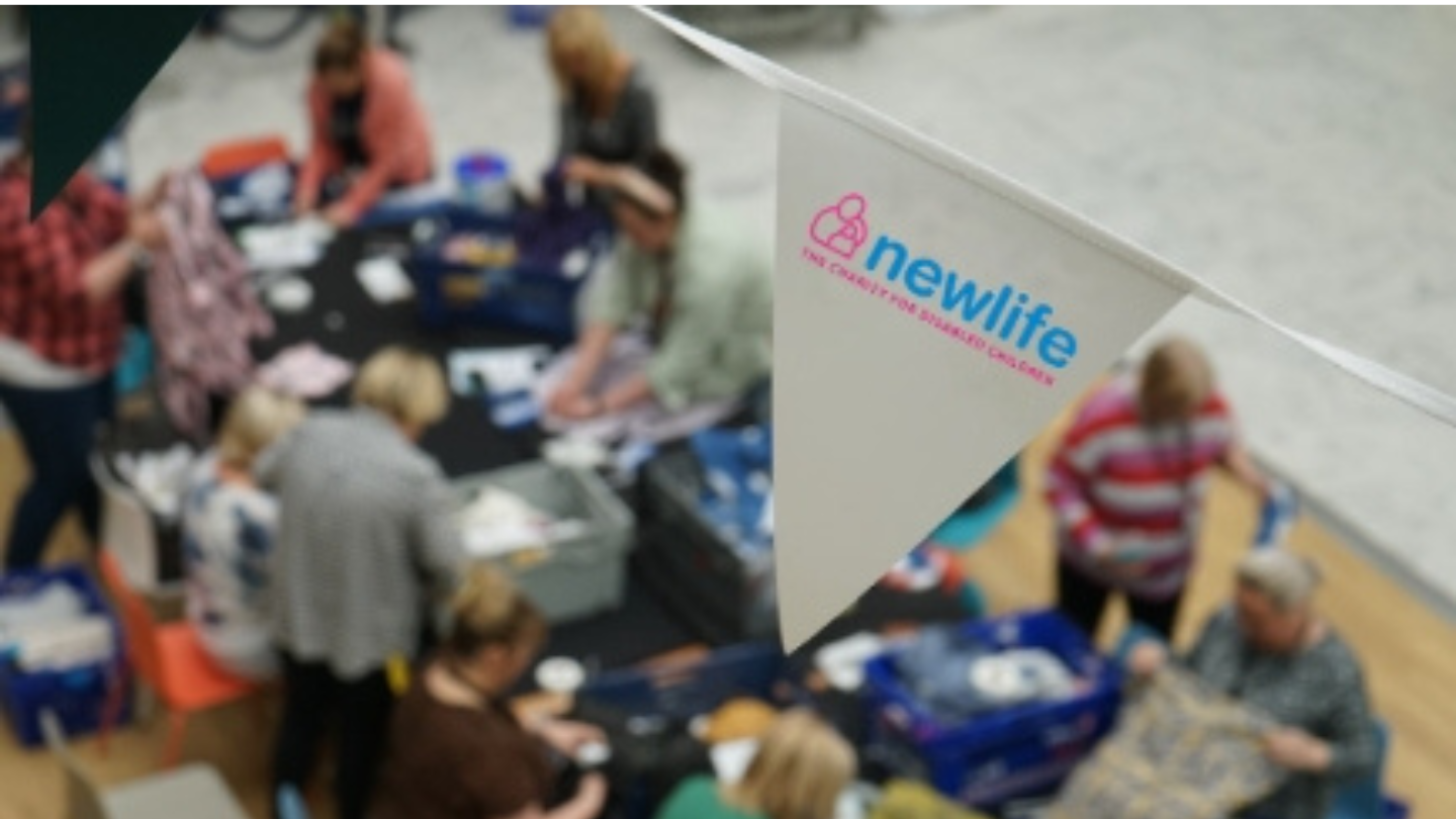Close up of a bunting flag with the Newlife logo on it over a table at a charity event.