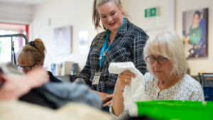 Picture shows Volunteer Manager working with a volunteer in the Newlife opportunities centre - sorting clothes for pricing and processing