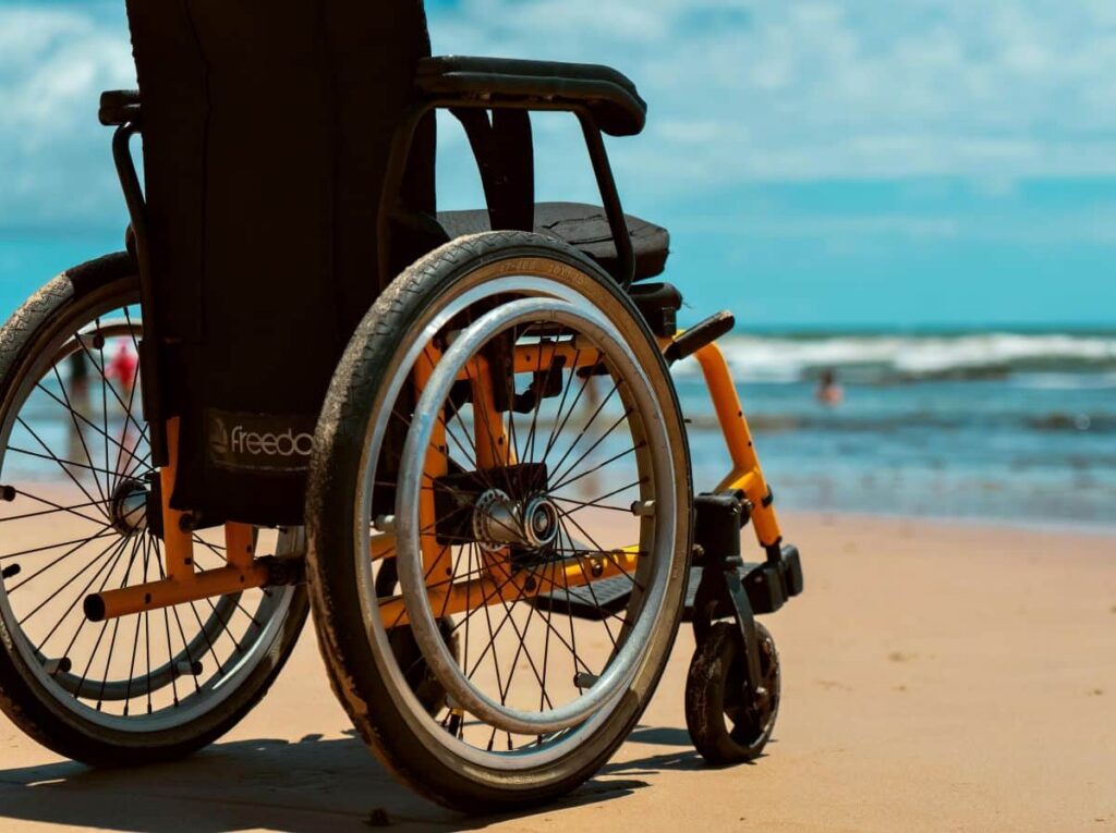 empty wheelchair placed on the sand overlooking the sea