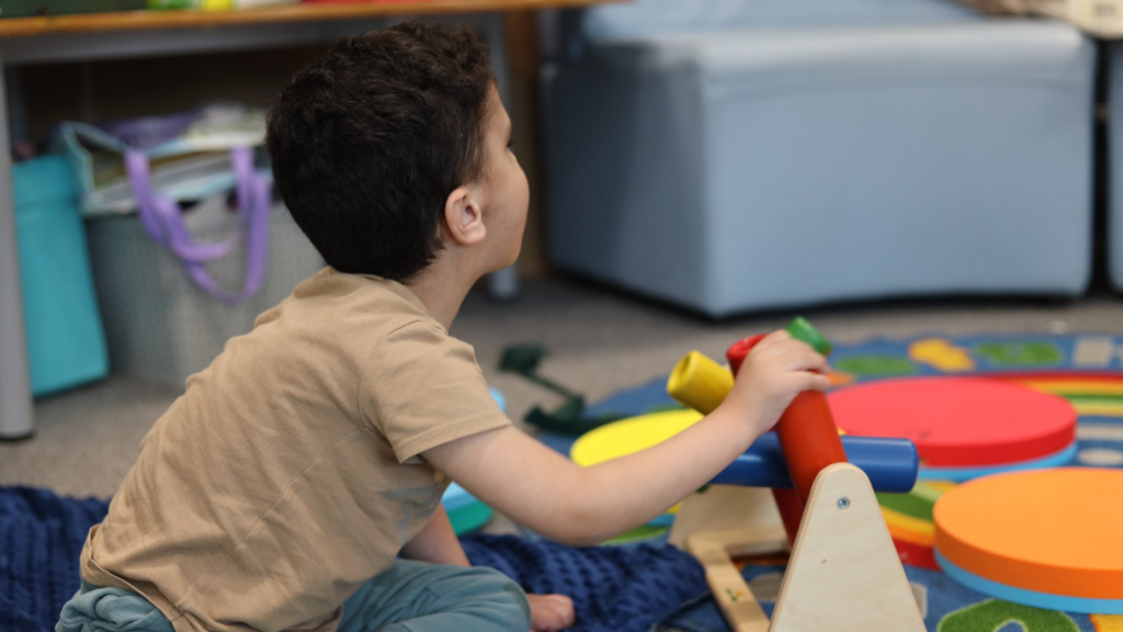 This image shows a boy playing on the carpet with sensory toys.