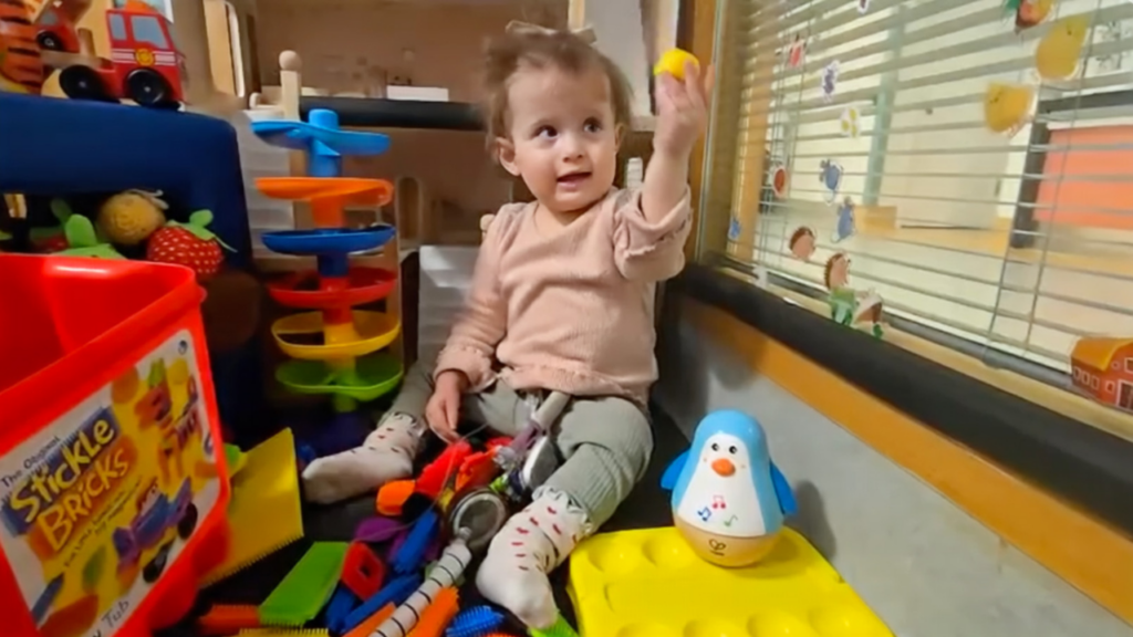 This image shows a child sitting amongst toys.