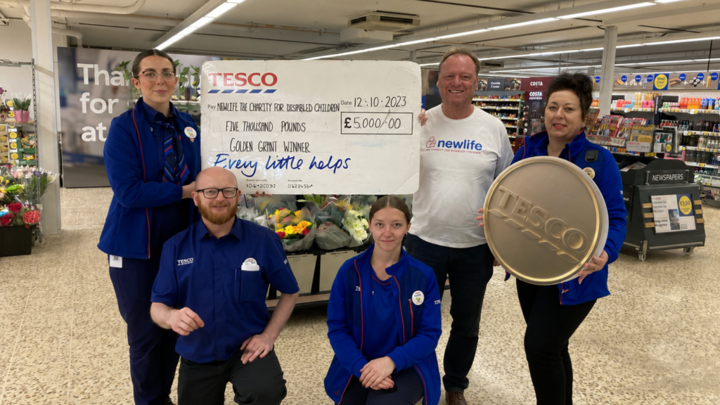Image shows tesco workers holding up a cheque for Newlife